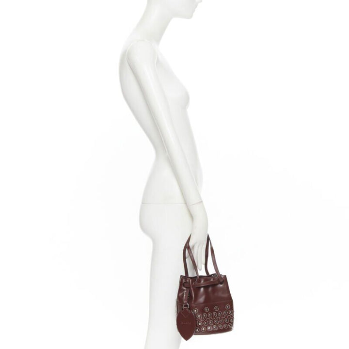 ALAIA burgundy red geometric silver studded drawstring mirror charm bucket bag